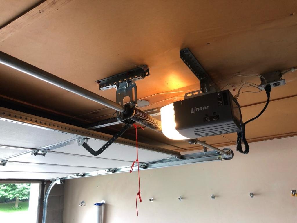Technician performing garage door opener installation in a residential garage in Upper Arlington, showcasing new equipment and wiring for optimal garage door functionality.
